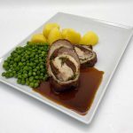 Saftiger Schweinebraten gefüllt mit getrockneten Tomaten und Pesto, Erbsen, Butterkartoffeln und Rotweinsoße